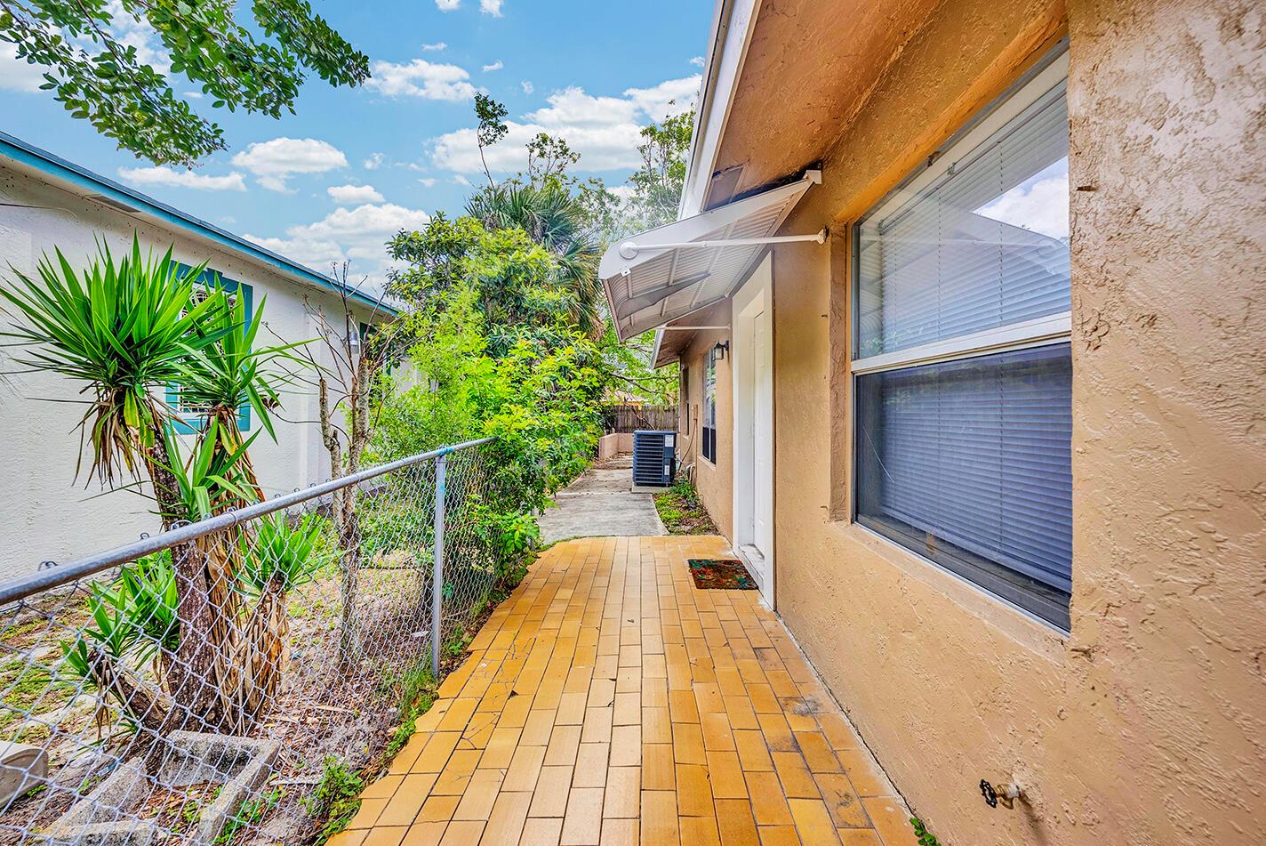 A paved walkway runs alongside a tan house with a window and a small awning — 336 NE 12th Avenue, Boynton Beach FL 33435, BOYNTON BEACH, FL