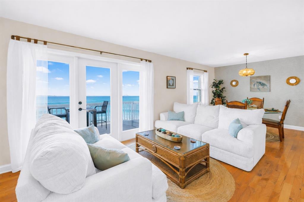 A living room with white sofas, a rattan coffee table, and ocean views through doors — 5102 COQUINA KEY DRIVE SE UNIT D, ST PETERSBURG, FL