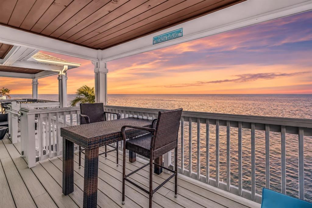 A covered balcony with outdoor furniture overlooks the ocean under a clear blue sky — 5102 COQUINA KEY DRIVE SE UNIT D, ST PETERSBURG, FL