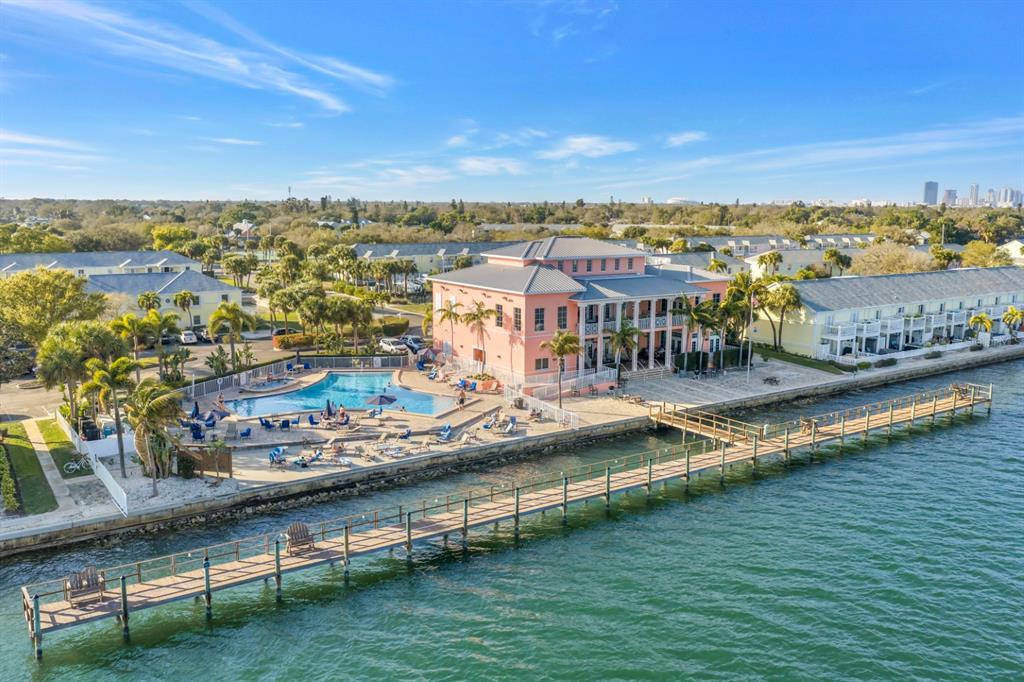 An aerial view shows a pink building with a pool and a long wooden pier — 5102 COQUINA KEY DRIVE SE UNIT D, ST PETERSBURG, FL