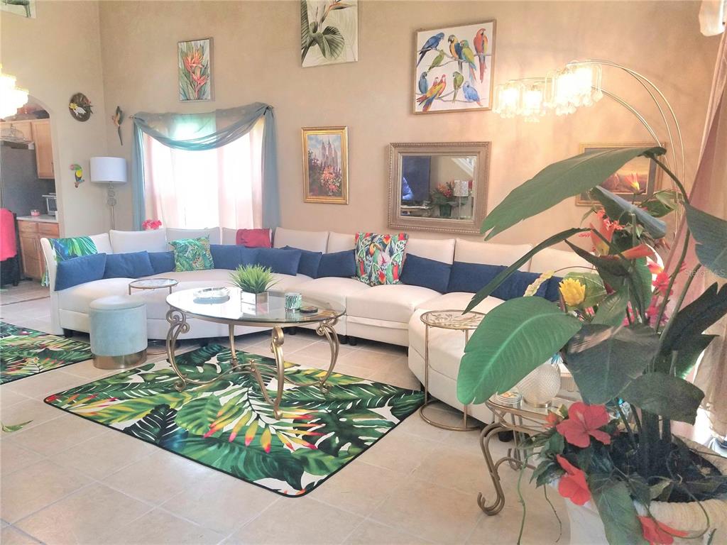 A living room features a large white sectional sofa, a glass coffee table, and tropical decor — 12900 WINFIELD SCOTT BOULEVARD, ORLANDO, FL