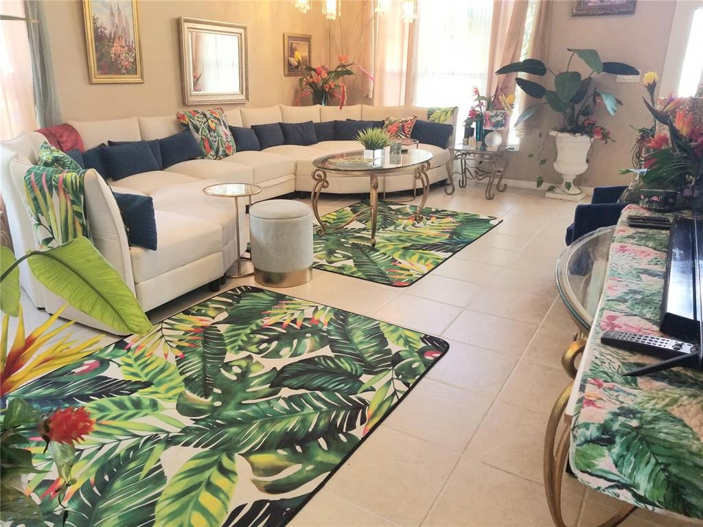 A living room features a large white sectional sofa, tropical-patterned rugs, and tiled flooring — 12900 WINFIELD SCOTT BOULEVARD, ORLANDO, FL