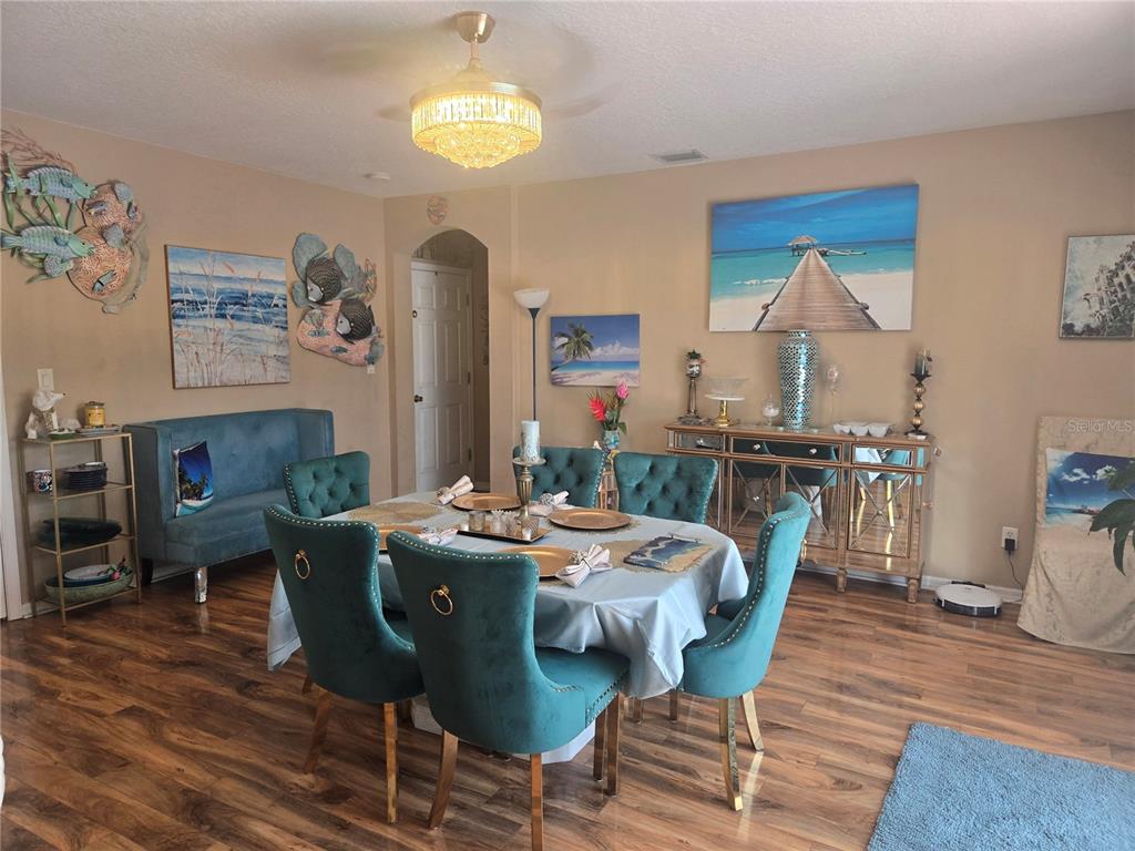 A dining room features a table with teal velvet chairs, a chandelier, and coastal decor — 12900 WINFIELD SCOTT BOULEVARD, ORLANDO, FL