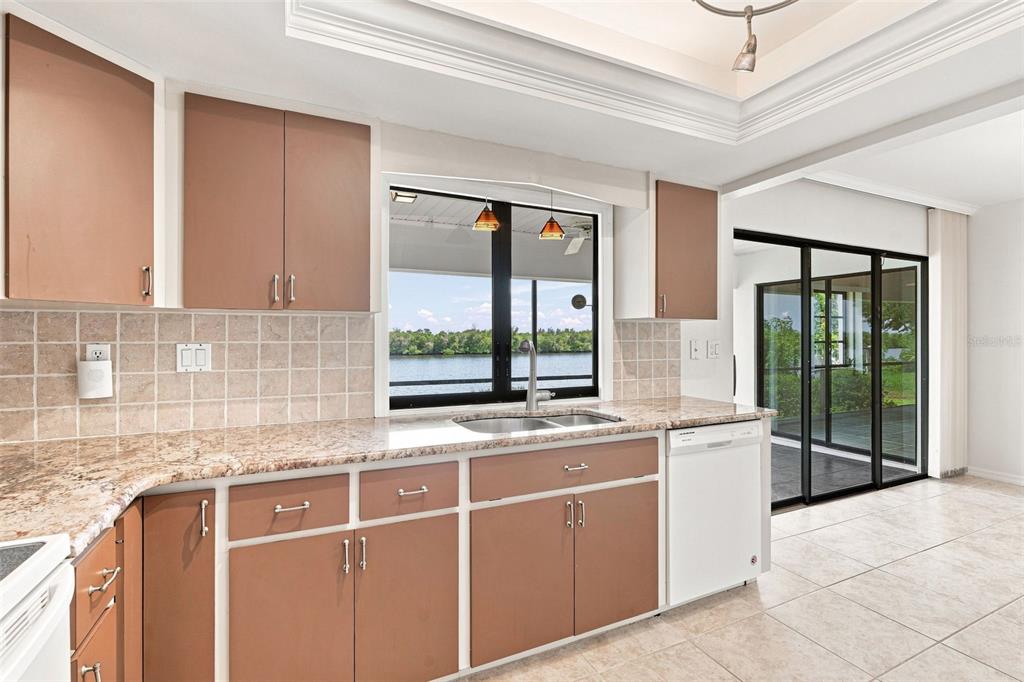 A kitchen with brown cabinets, granite countertops, a double sink, and a view of water — 18422 ARAPAHOE CIRCLE, PORT CHARLOTTE, FL