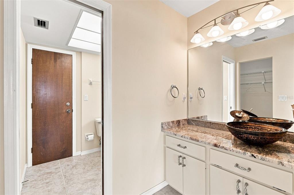 A bathroom features a granite vanity with a vessel sink, a mirror, and a door — 18422 ARAPAHOE CIRCLE, PORT CHARLOTTE, FL