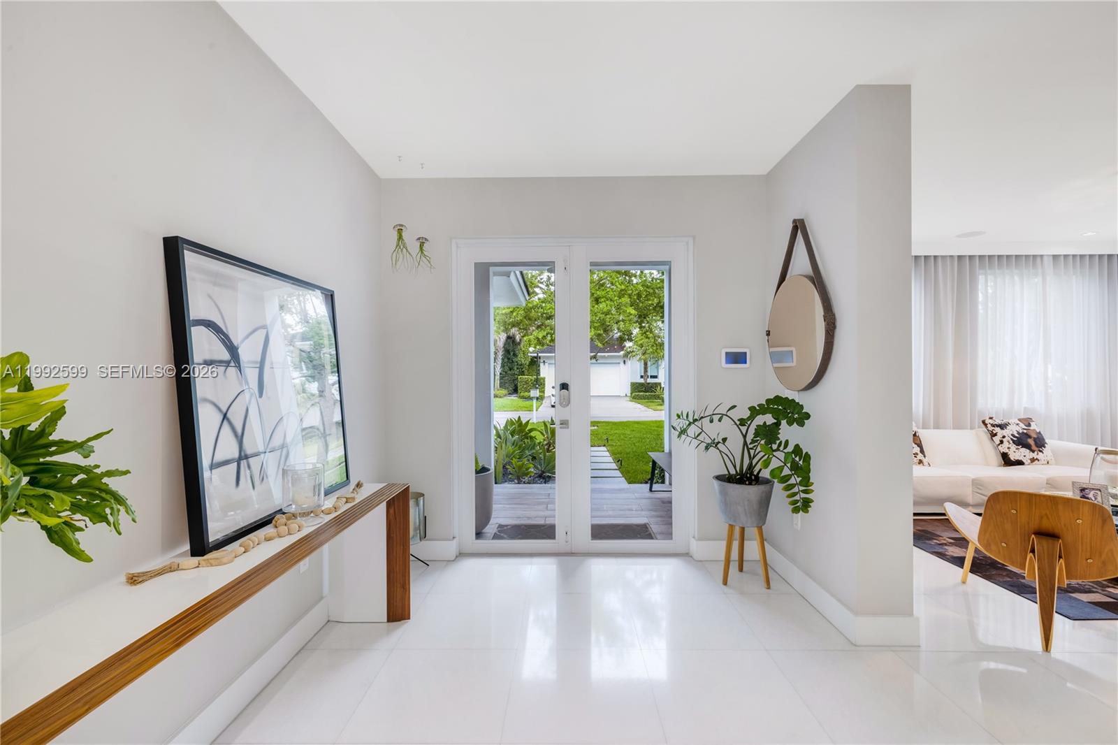 A bright entryway features white tile floors, a wooden console table, and glass double doors — 5602 SW 65th Ct, South Miami FL 33143, SOUTH MIAMI, FL