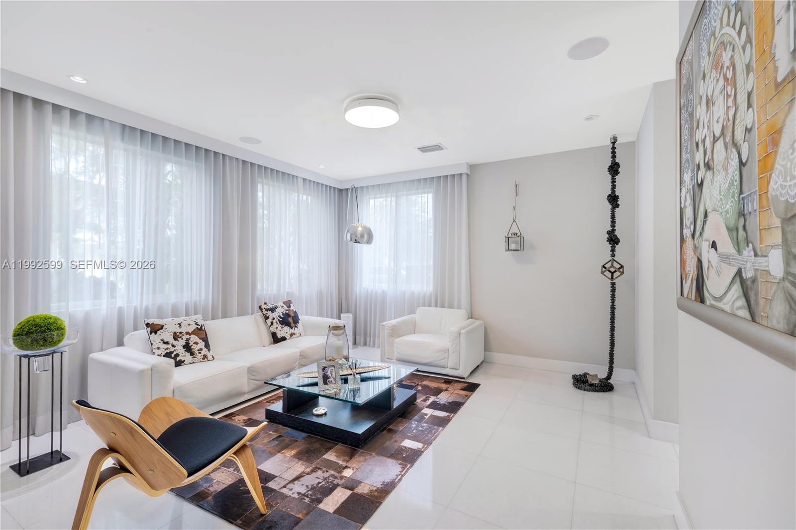 A modern living room features white furniture, a patterned rug, and a large wall painting — 5602 SW 65th Ct, South Miami FL 33143, SOUTH MIAMI, FL