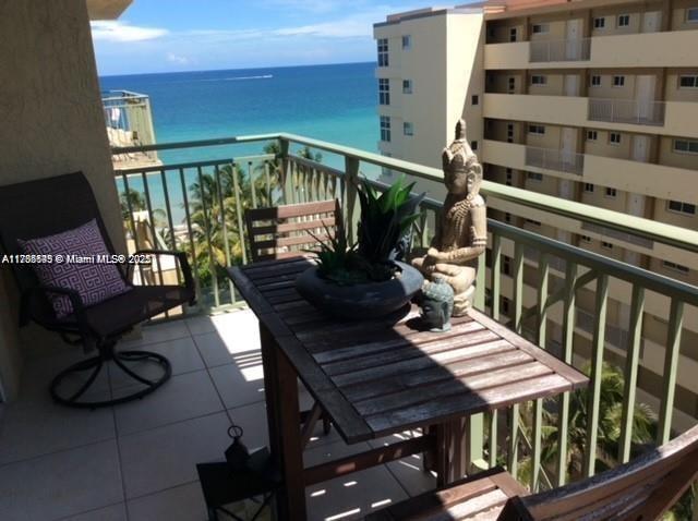 A balcony features a wooden table, a chair with a patterned pillow, and ocean views — 2080 S Ocean Dr # 707, Hallandale Beach FL 33009, HALLANDALE BEACH, FL