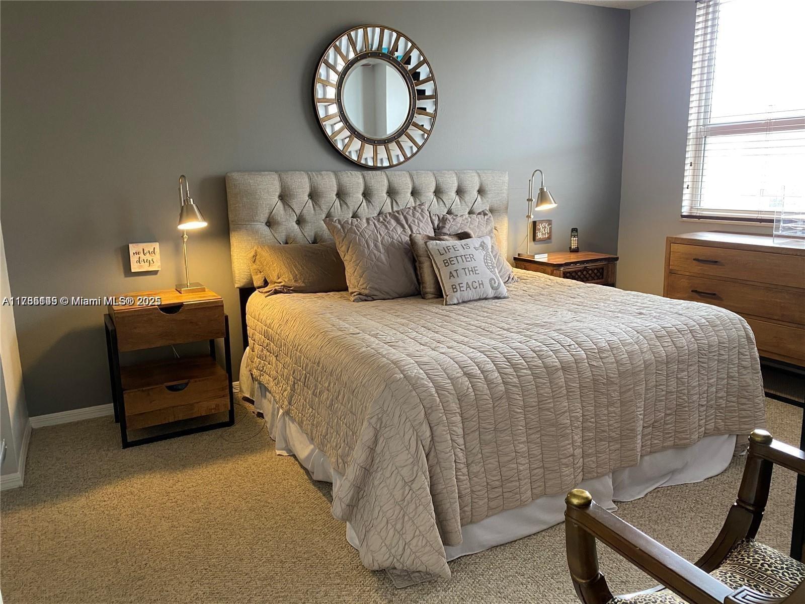 A bedroom features a tufted headboard, a round wall mirror, and two wooden nightstands — 2080 S Ocean Dr # 707, Hallandale Beach FL 33009, HALLANDALE BEACH, FL