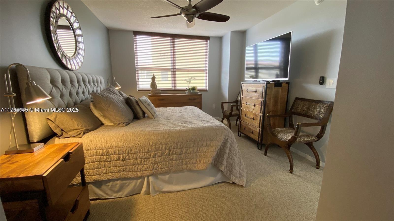 A bedroom features a tufted headboard, a wooden dresser with a television, and two chairs — 2080 S Ocean Dr # 707, Hallandale Beach FL 33009, HALLANDALE BEACH, FL