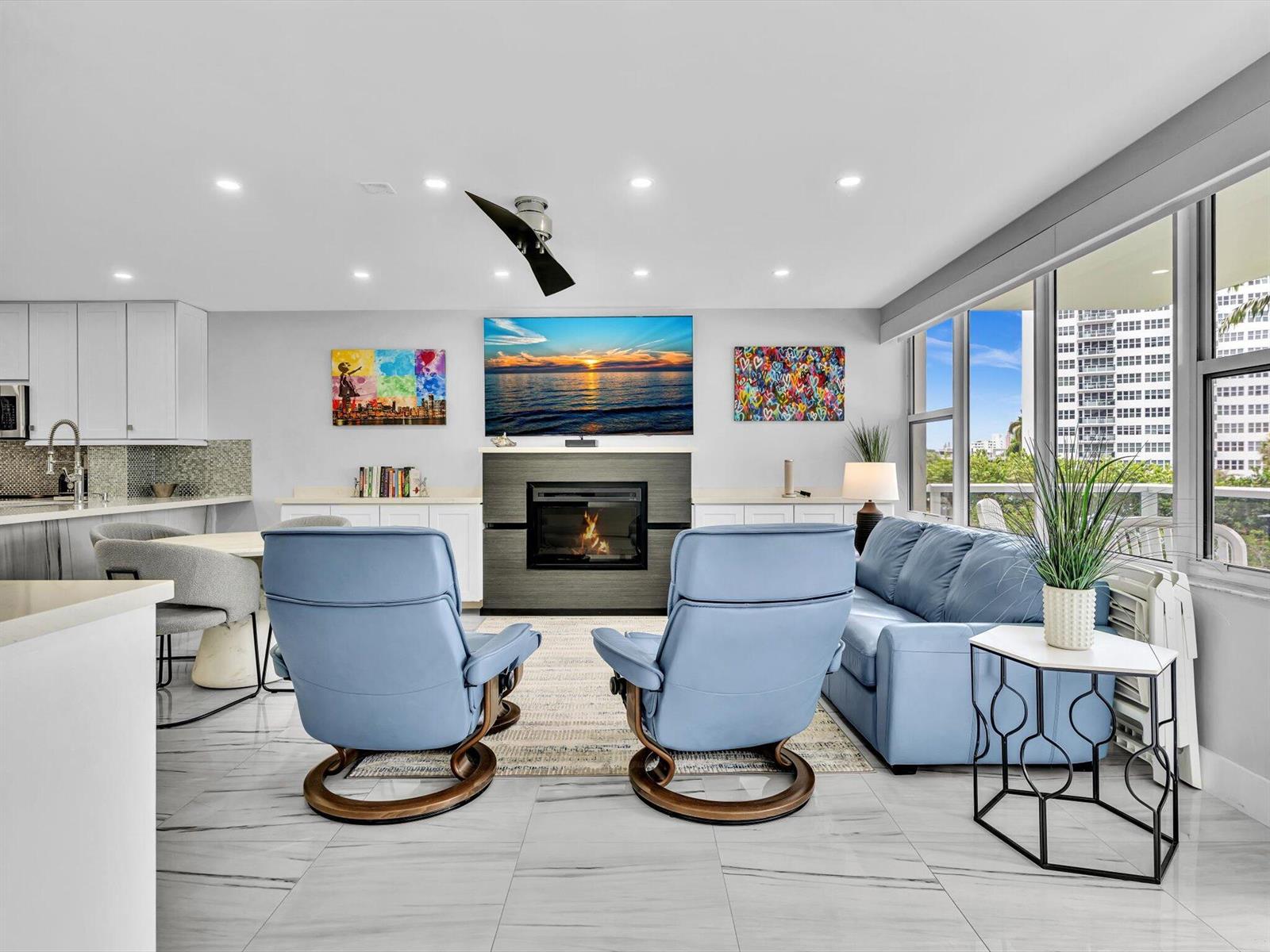 A living room features two blue armchairs, a fireplace, a television, and large windows — 3300 NE 36th Street # 217, FL 33308, FL