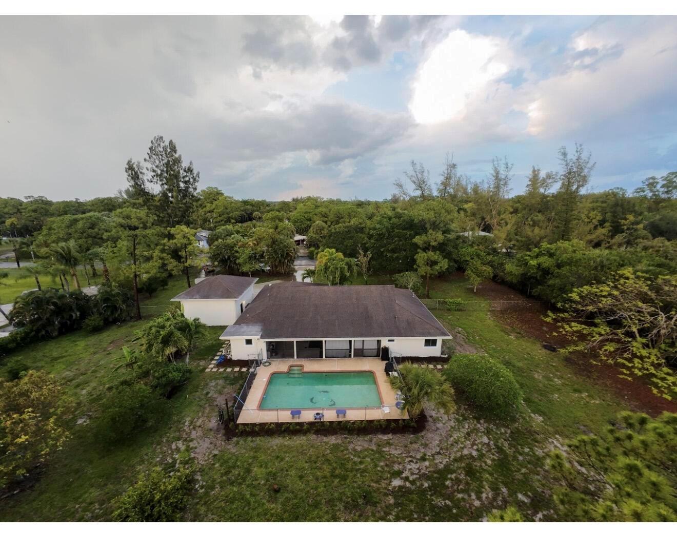 An aerial view of a house with a swimming pool surrounded by a large grassy yard — 8264 Palomino Drive, Lake Worth FL 33467, LAKE WORTH, FL
