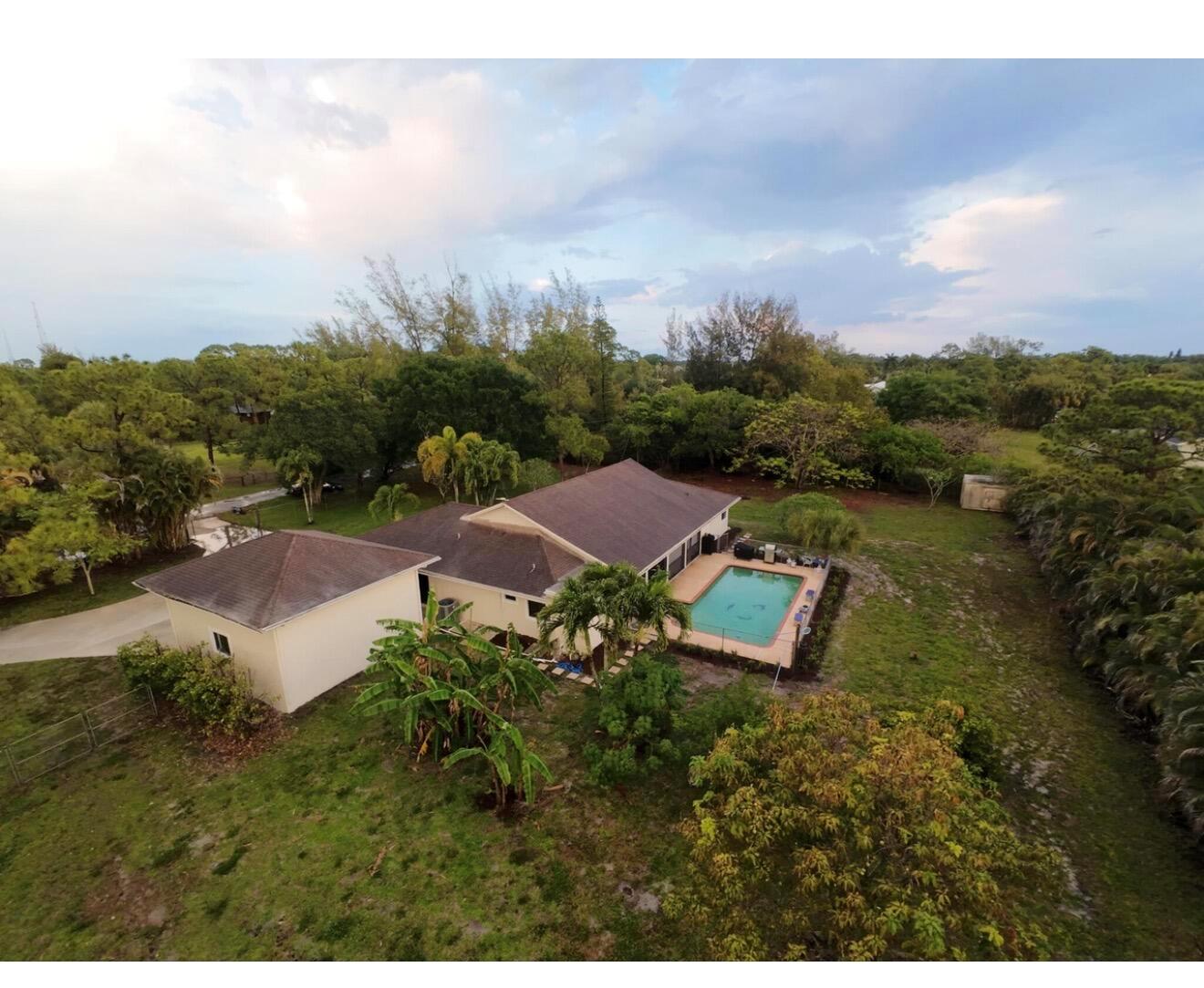 An aerial view of a house with a swimming pool surrounded by a large yard — 8264 Palomino Drive, Lake Worth FL 33467, LAKE WORTH, FL