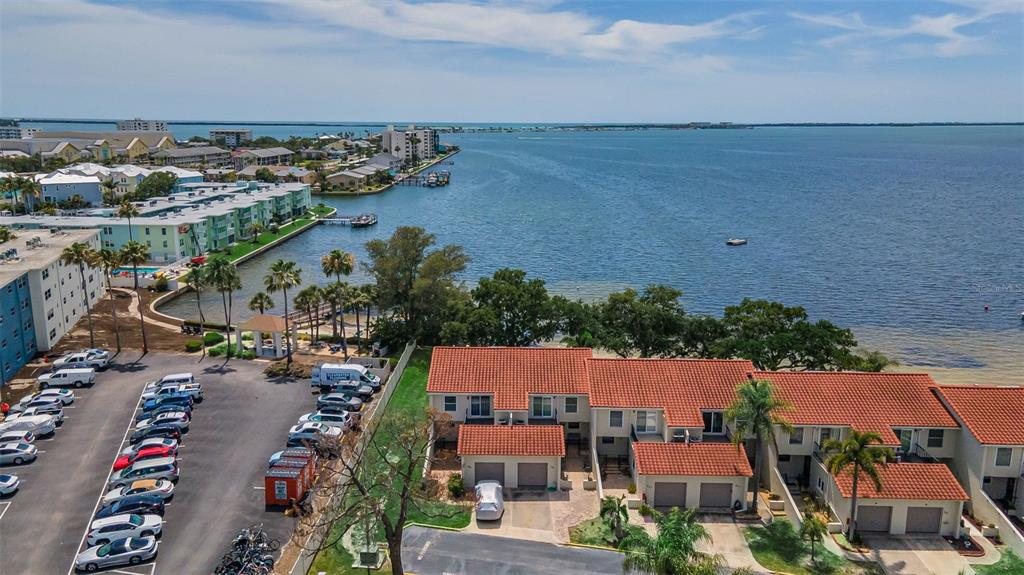 An aerial view shows a waterfront townhouse complex with a parking lot and bay — 2700 BAYSHORE BOULEVARD UNIT 525, DUNEDIN, FL
