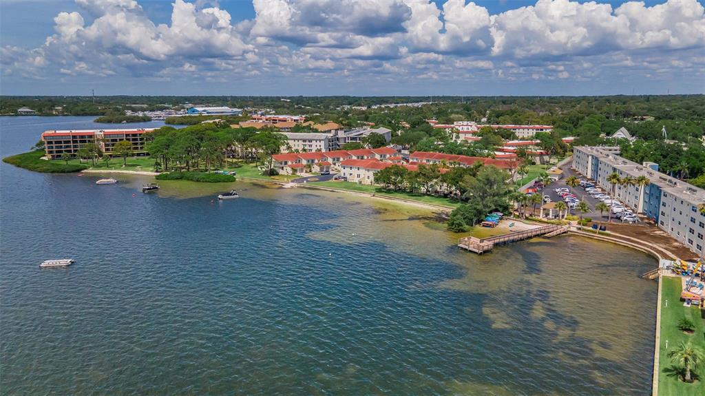 An aerial view of waterfront apartment buildings with a pier and boats on the water — 2700 BAYSHORE BOULEVARD UNIT 525, DUNEDIN, FL