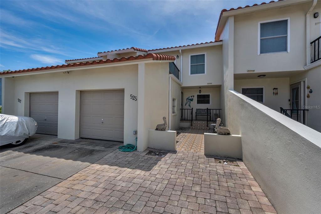 A two-story townhouse exterior features a paved driveway, two garage doors, and a front entryway — 2700 BAYSHORE BOULEVARD UNIT 525, DUNEDIN, FL