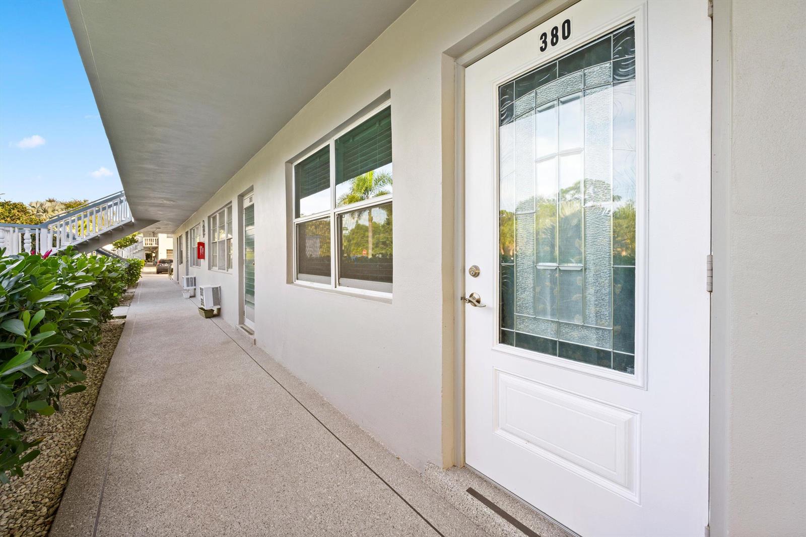 An exterior walkway leads past a white door marked 380 and several windows — 380 Sheffield P, West Palm Beach FL 33417, WEST PALM BEACH, FL
