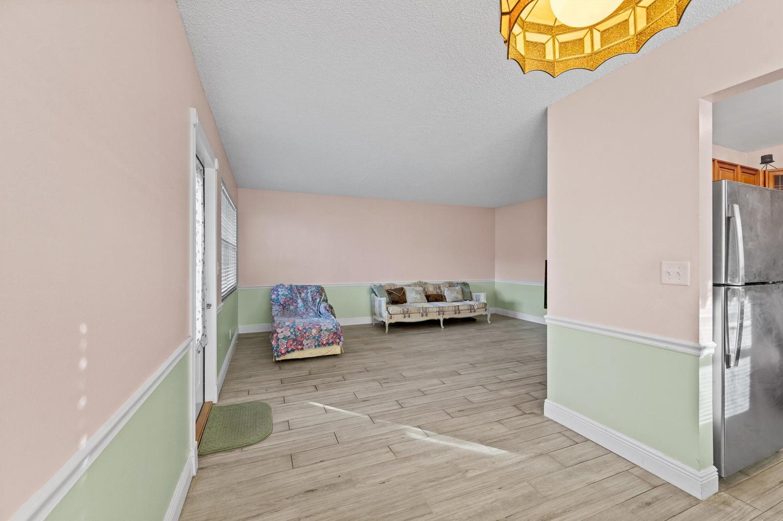 A living room features light pink and green walls, wood-look tile flooring, and a sofa — 380 Sheffield P, West Palm Beach FL 33417, WEST PALM BEACH, FL