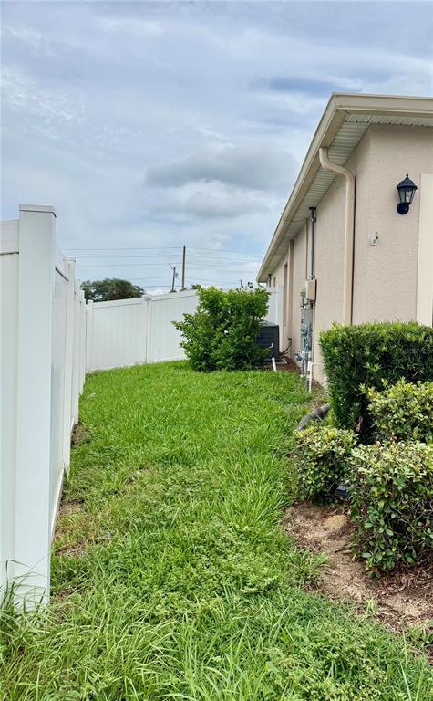 A side yard features a white vinyl fence, a patch of grass, and exterior landscaping — 196 TRACY COURT E, HAINES CITY, FL
