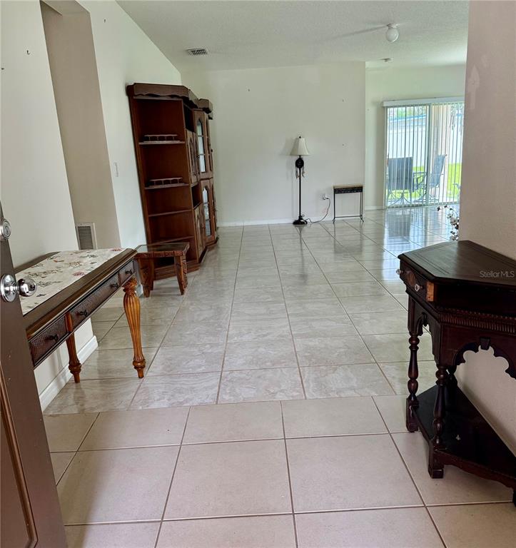 A tiled living area features a wooden hutch, two side tables, and a sliding glass door — 196 TRACY COURT E, HAINES CITY, FL