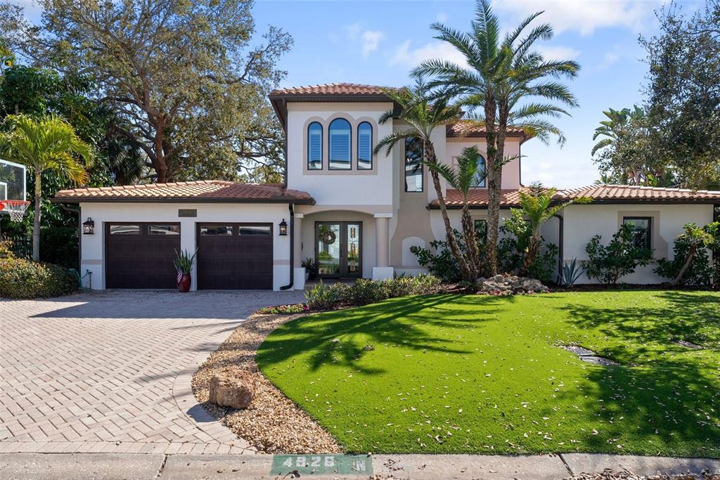 A two-story stucco house with a tile roof, two-car garage, and a landscaped front yard — 4926 W MELROSE AVENUE N, TAMPA, FL
