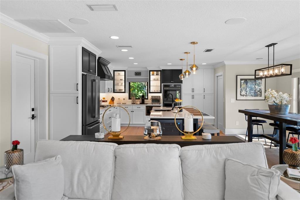 A modern kitchen features white cabinetry, a large quartz island, and black accents throughout — 4926 W MELROSE AVENUE N, TAMPA, FL