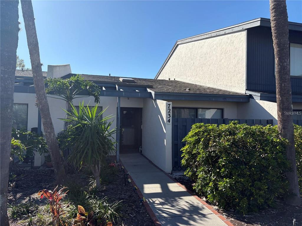 A walkway leads to the front entrance of a two-story home with a stucco exterior — 7234 CLOISTER DRIVE UNIT 7234, SARASOTA, FL