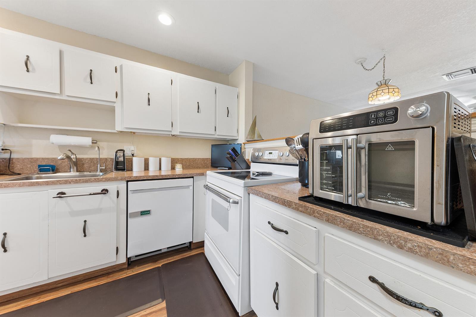 A kitchen features white cabinets, laminate countertops, a white stove, and a stainless steel air fryer — 1060 Citrus Way # 204, Delray Beach FL 33445, DELRAY BEACH, FL