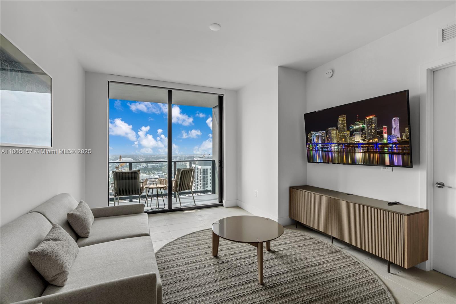 A modern living room features a sofa, round rug, media console, and a balcony view — 601 NE 1st # 4204, Miami FL 33132, MIAMI, FL