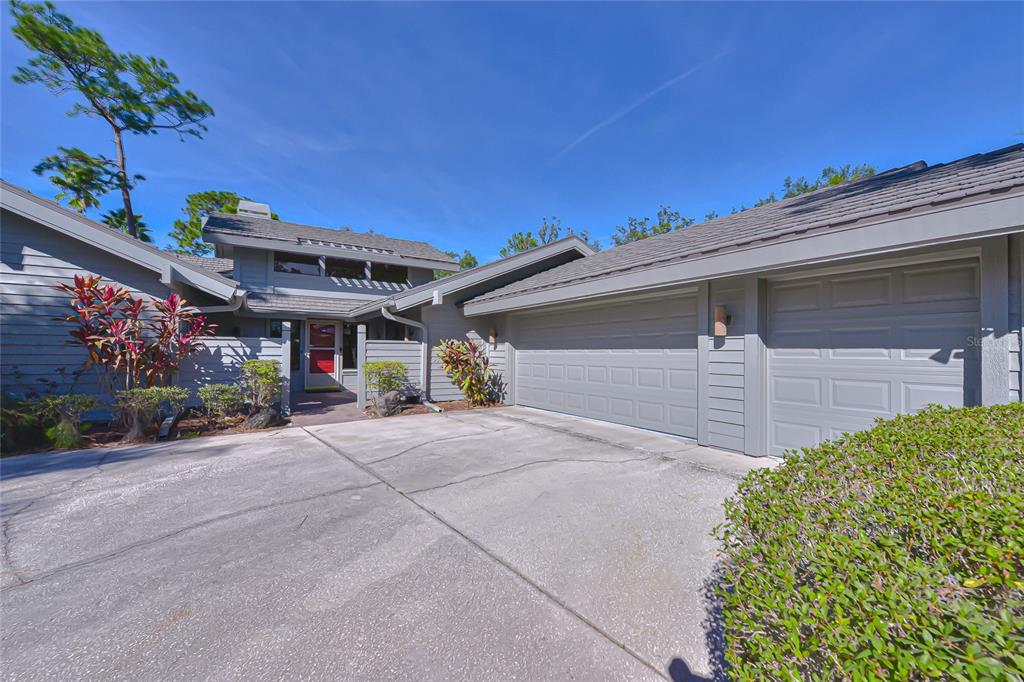 A gray house with a two-car garage and a concrete driveway under a blue sky — 5355 COBBLESTONE COURT, WESLEY CHAPEL, FL