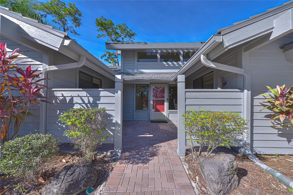 A gray house exterior features a brick walkway leading to a central front entrance — 5355 COBBLESTONE COURT, WESLEY CHAPEL, FL