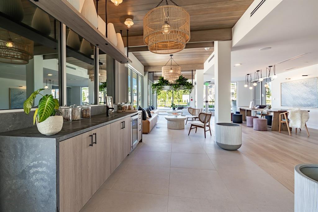 A modern lounge area features light wood cabinetry, woven pendant lights, and a wooden ceiling — 11929 PIONEERS WAY UNIT A2, ORLANDO, FL