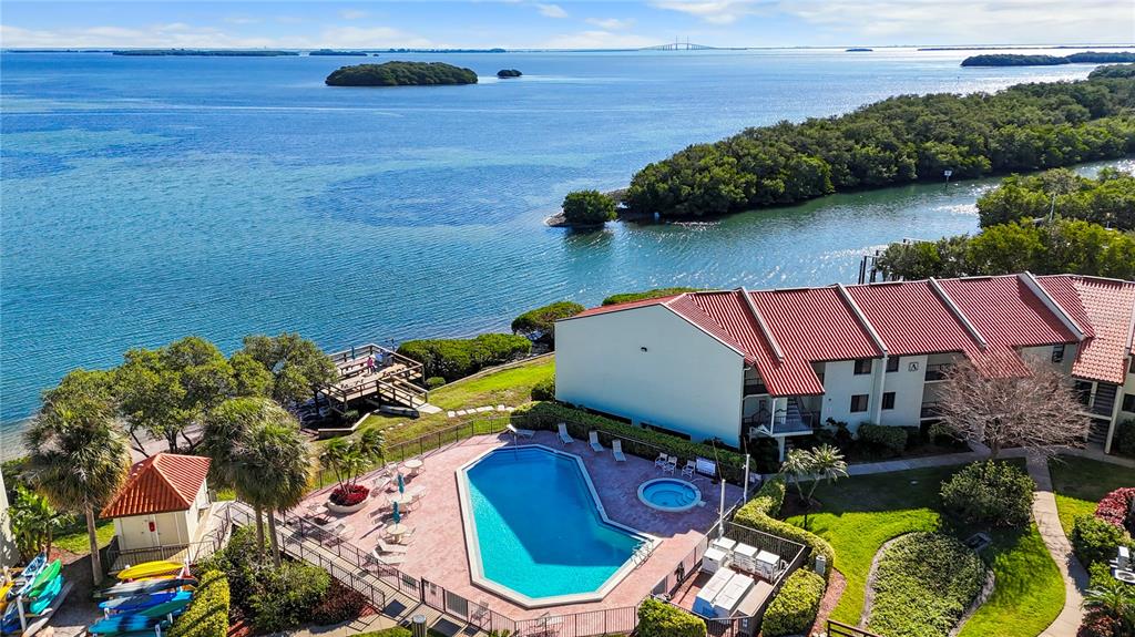 An aerial view shows a swimming pool, a multi-story building, and a dock by water — 1515 PINELLAS BAYWAY S UNIT 7, TIERRA VERDE, FL