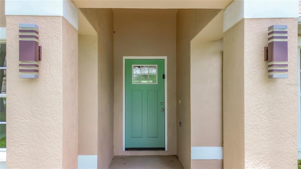 A front entryway features a light green door flanked by two wall-mounted outdoor light fixtures — 213 LINDER DRIVE, HOMOSASSA, FL
