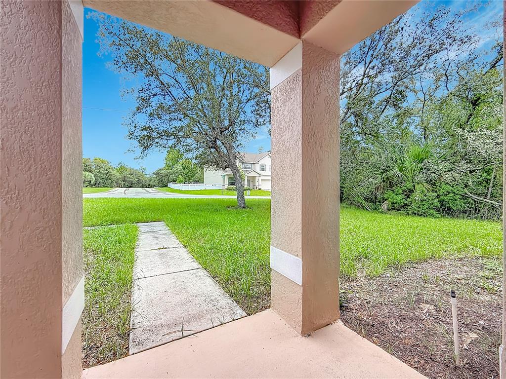 A view from a covered porch looking out toward a sidewalk, lawn, and neighboring house — 213 LINDER DRIVE, HOMOSASSA, FL