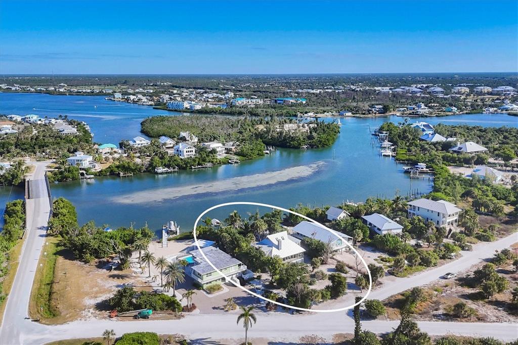An aerial view shows waterfront homes with metal roofs surrounded by trees and sandy grounds — 30 GASPARILLA WAY, PLACIDA, FL
