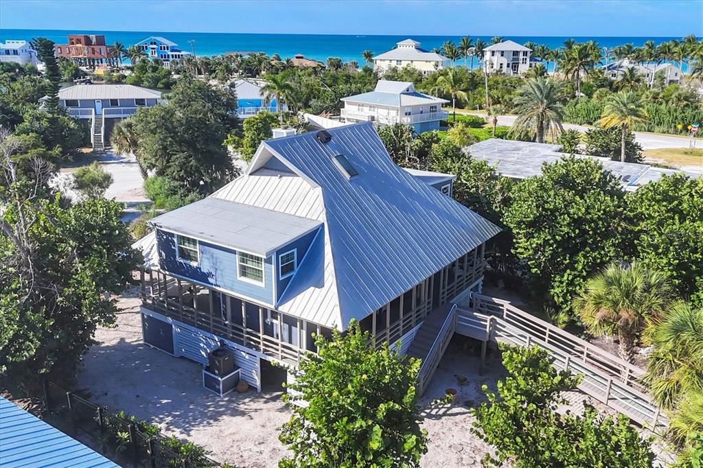 An aerial view of a blue two-story house with a metal roof near the ocean — 30 GASPARILLA WAY, PLACIDA, FL