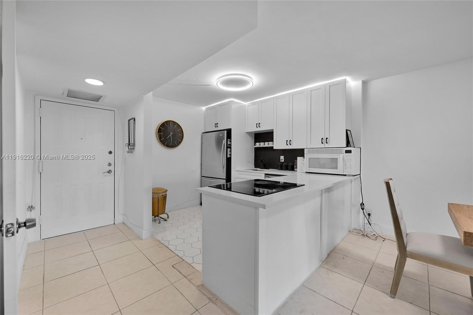 This kitchen features white cabinets, a black backsplash, a glass cooktop, and light-colored tile flooring — 400 Leslie Dr # 605, Hallandale Beach FL 33009, HALLANDALE BEACH, FL