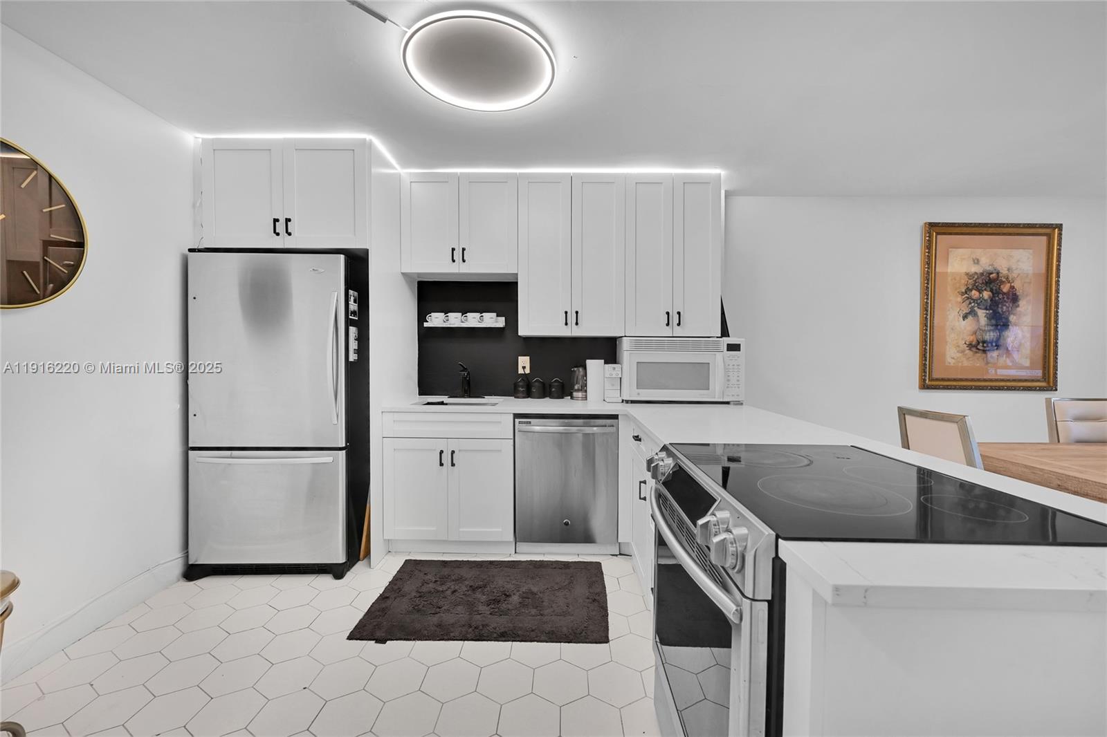A modern kitchen features white cabinetry, stainless steel appliances, and a white hexagonal tile floor — 400 Leslie Dr # 605, Hallandale Beach FL 33009, HALLANDALE BEACH, FL
