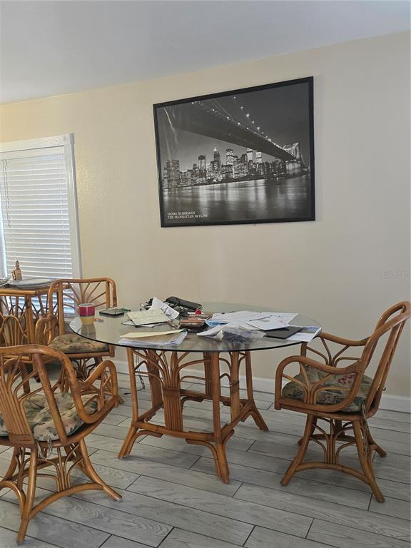 A dining area features a glass-topped rattan table, matching chairs, and a large skyline print — 7146 E BANK DRIVE UNIT 7146, TAMPA, FL