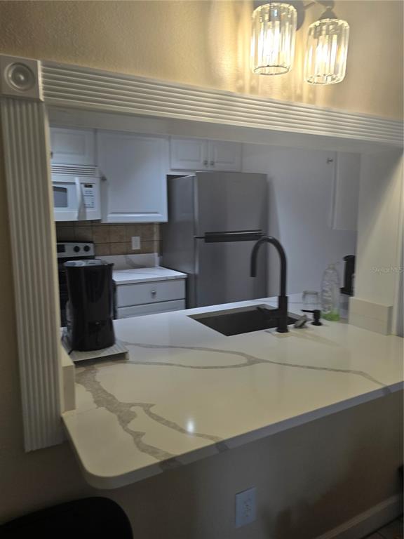 A kitchen features white cabinets, stainless steel appliances, and a white quartz countertop with veining — 7146 E BANK DRIVE UNIT 7146, TAMPA, FL