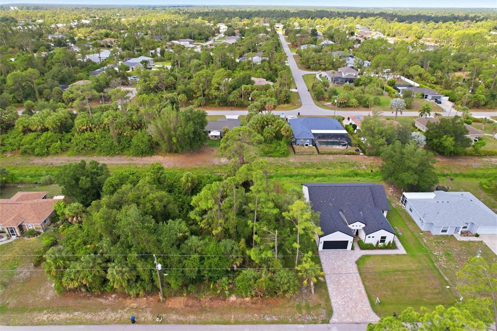 An aerial view shows a residential property with a house, driveway, and wooded lot — OREGON LANE, NORTH PORT, FL