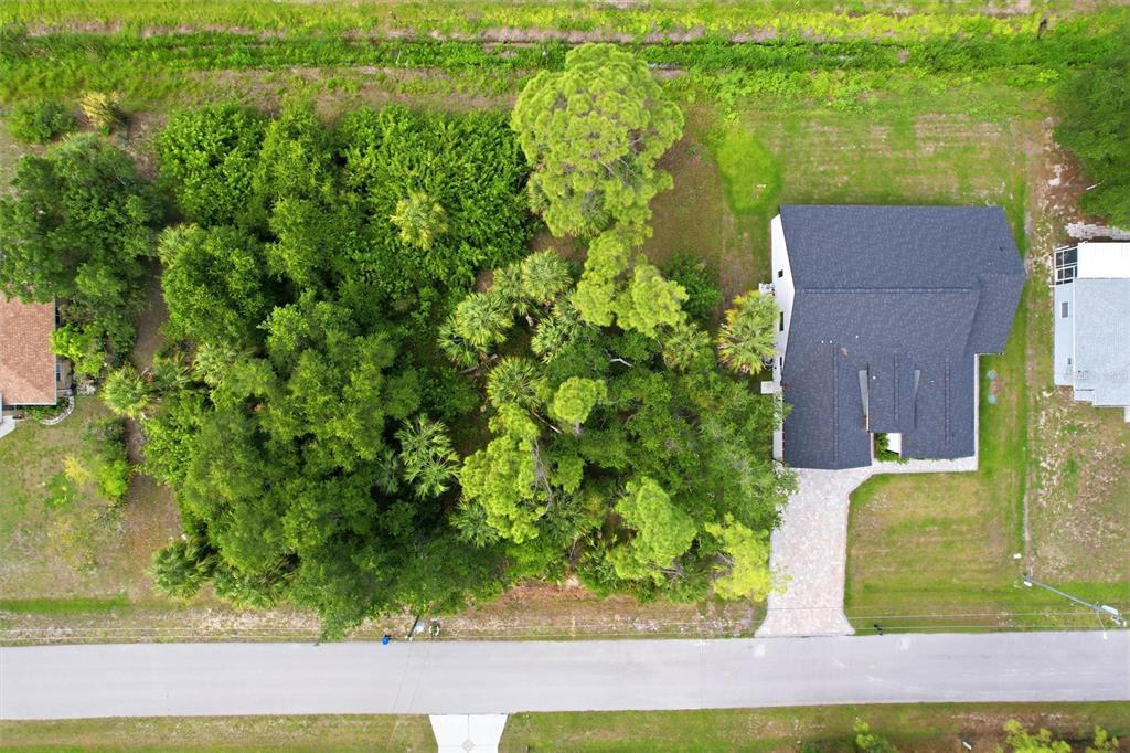 An aerial view shows a house with a dark roof next to a wooded lot — OREGON LANE, NORTH PORT, FL