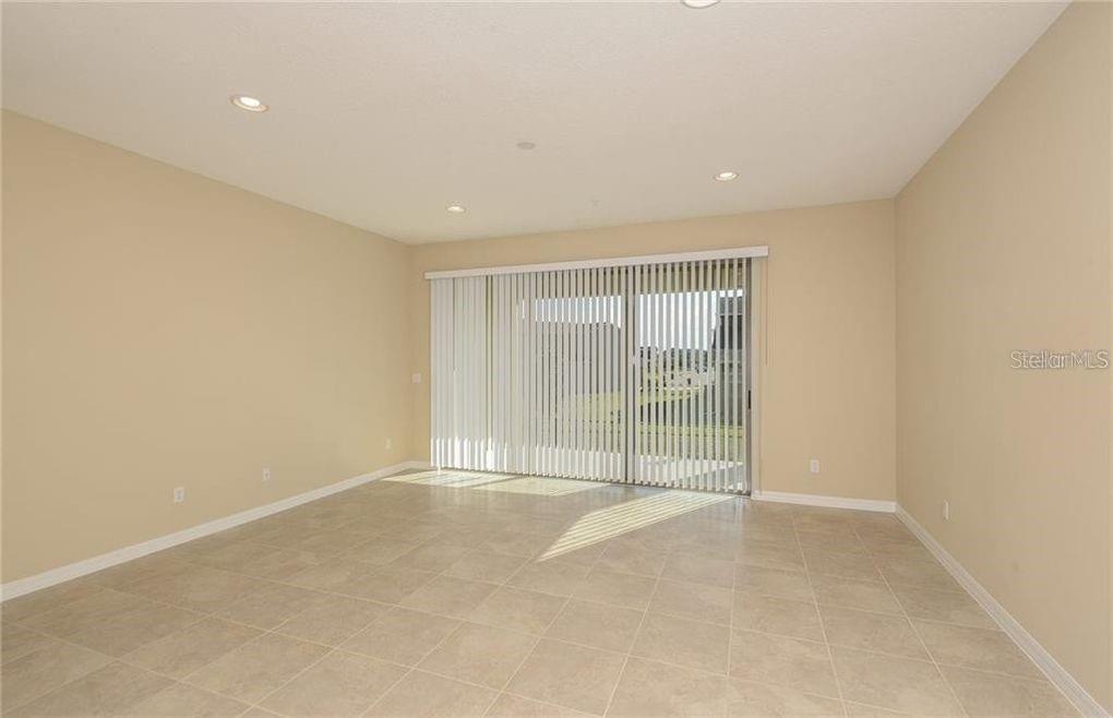 An empty room with beige walls, tile flooring, and a sliding glass door with blinds — 3890 GRASSLAND DRIVE, ORLANDO, FL