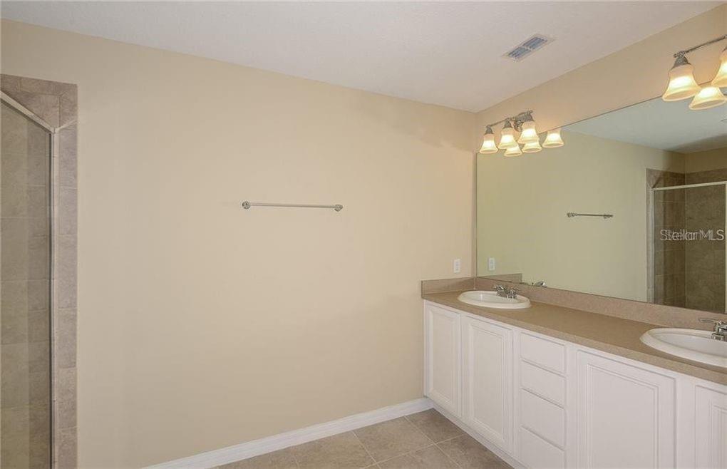 A bathroom features a double vanity with white cabinets, a large mirror, and tiled flooring — 3890 GRASSLAND DRIVE, ORLANDO, FL