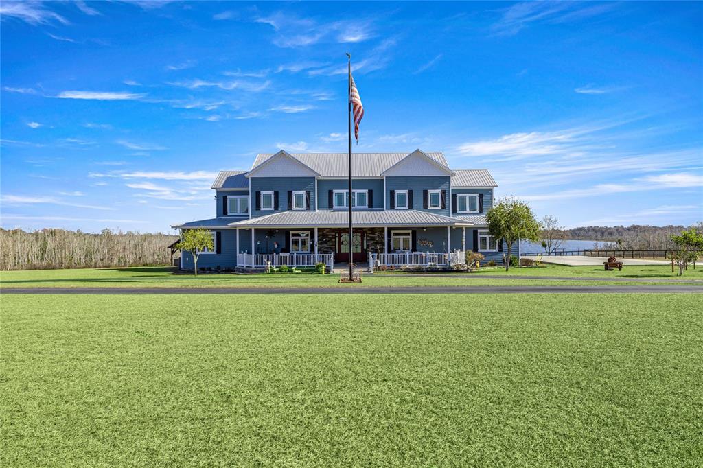 A two-story blue house with a metal roof and a large front porch sits outdoors — 5251 SE 180TH AVENUE ROAD, OCKLAWAHA, FL