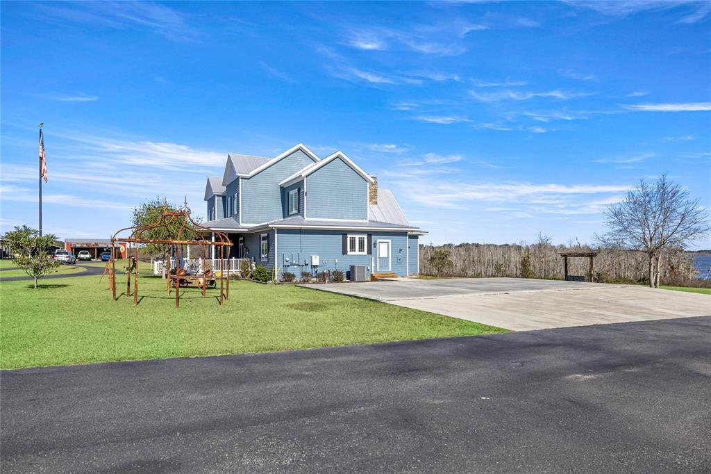 A blue two-story house with a metal roof sits beside a concrete patio and lawn — 5251 SE 180TH AVENUE ROAD, OCKLAWAHA, FL