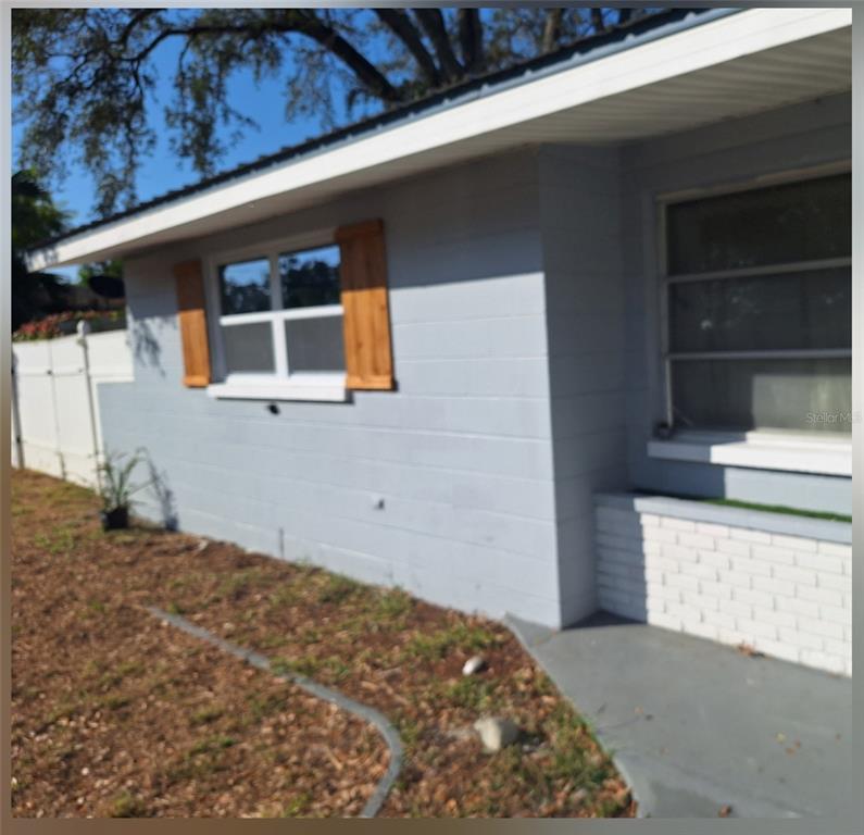A kitchen features white cabinets, stainless steel appliances, a dark island, and a sliding door — 10468 108TH STREET, LARGO, FL