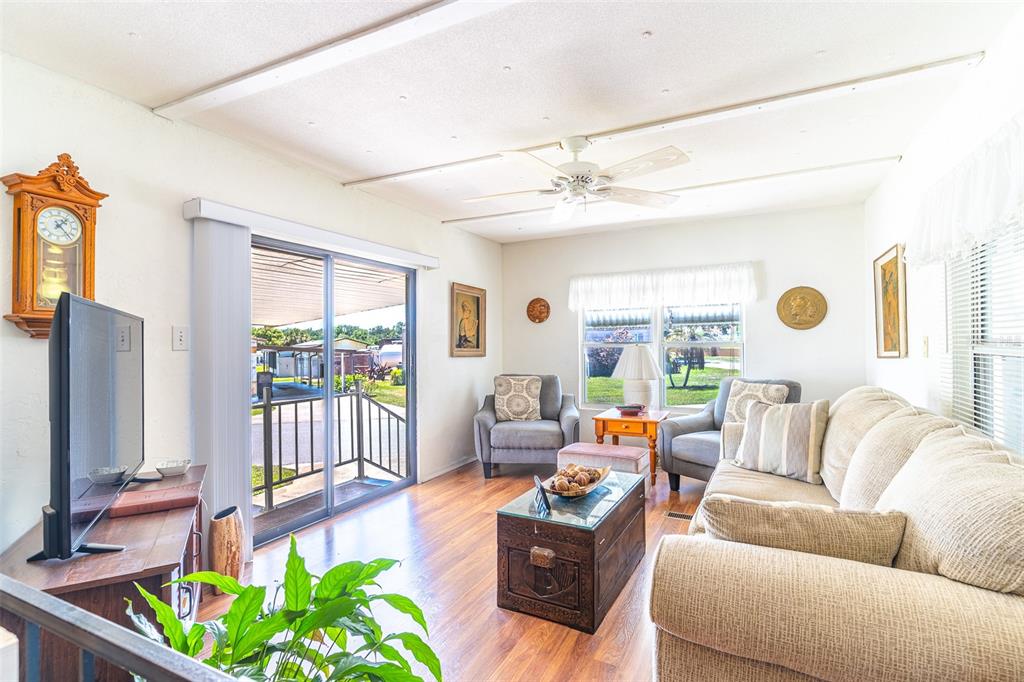 A living room features wood-look flooring, a ceiling fan, a sofa, and sliding glass doors — 107 EDGEWOOD BOULEVARD, LAKE WALES, FL