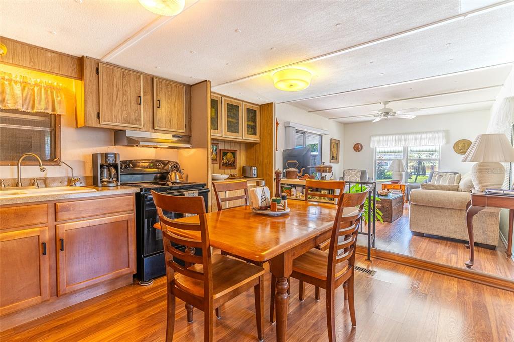 A kitchen with wood cabinets and a dining area opening into a living room — 107 EDGEWOOD BOULEVARD, LAKE WALES, FL